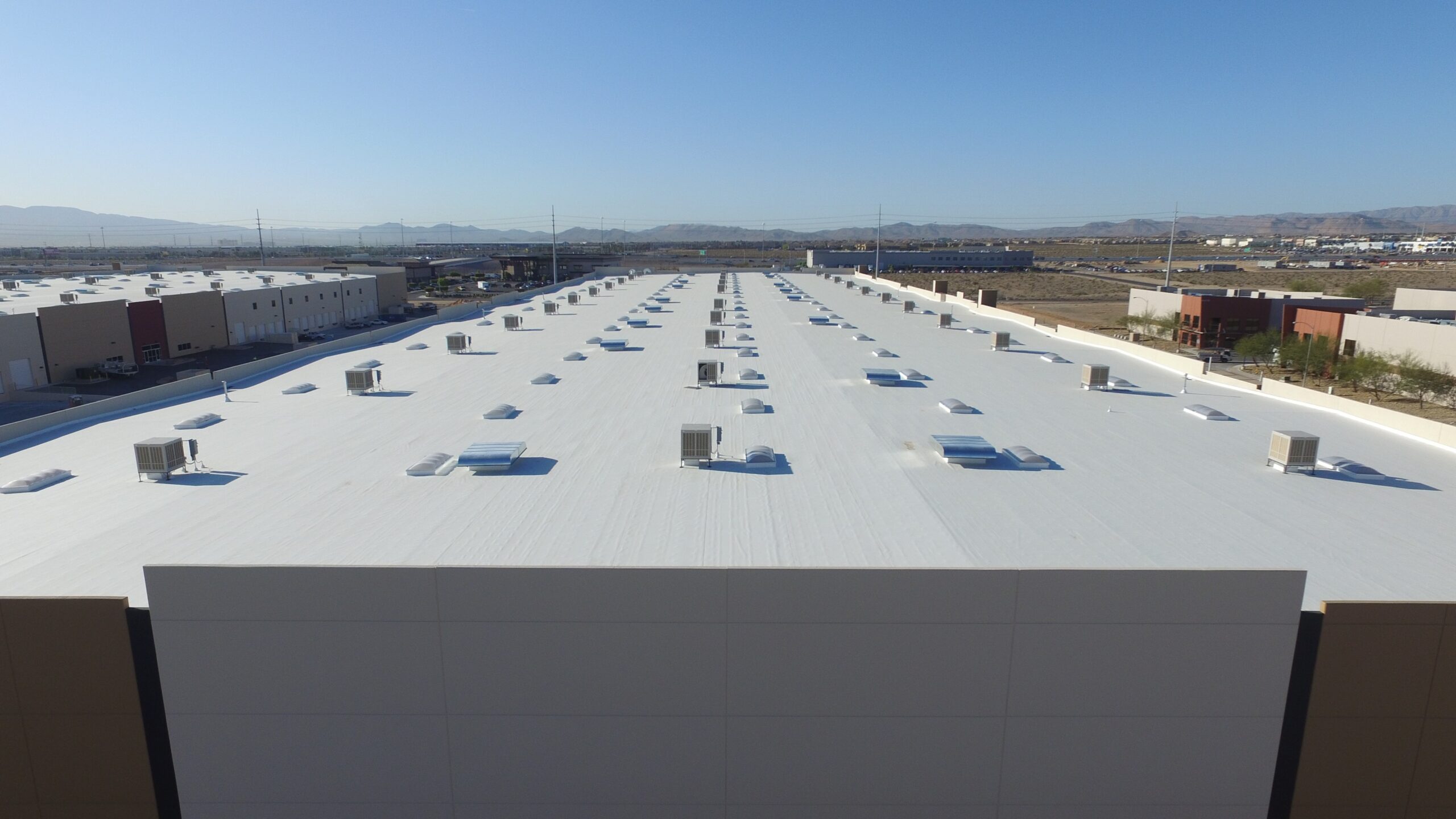 White commercial building rooftop with multiple HVAC units and skylights