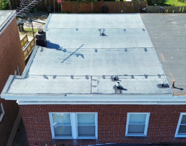 Aerial view of white flat roof on brick building with HVAC equipment and vents
