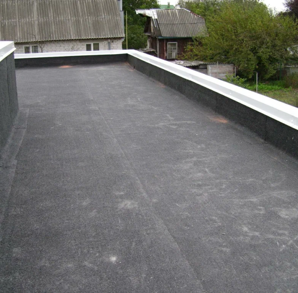 Flat roof with dark waterproof membrane and white edge trim on residential building