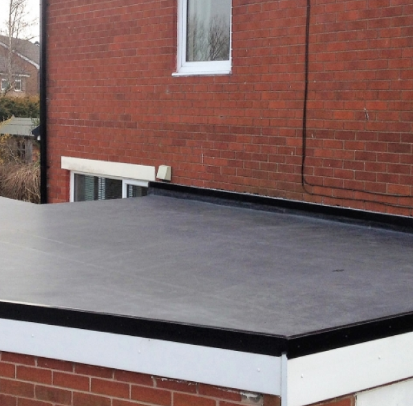 Flat roof extension with EPDM rubber membrane on brick house with white trim